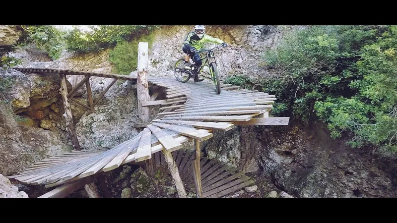 Ciclista bajando por una pasarela de madera en un Bike Park
